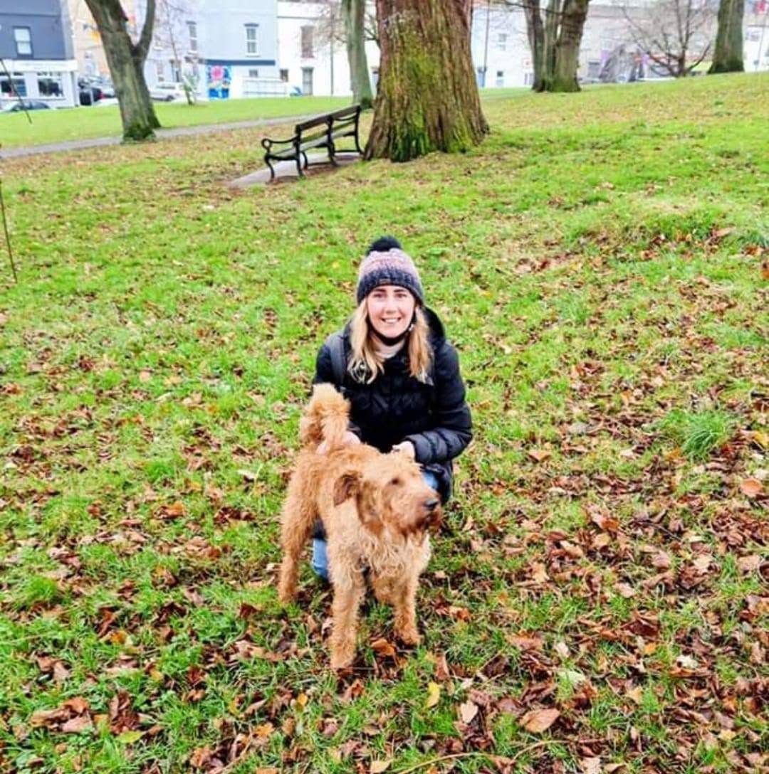 Gemma kneeling in a Bristol park with a scruffy Irish terrier